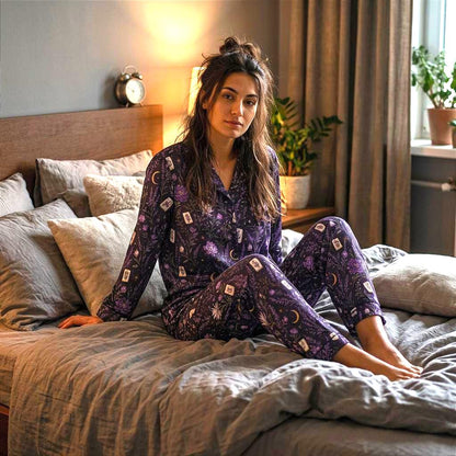 May include: A long-sleeved button-down pajama shirt and matching pants set in a dark purple fabric featuring a repeating pattern of white tarot cards, golden crescent moons, and various botanical illustrations including flowers and leafy stems.