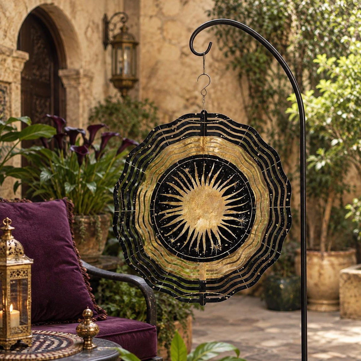 May include: A circular metal wind spinner featuring a black and gold sun design with radiating rays and small star accents. The spinner has a scalloped, wavy edge and is suspended from a black metal hook, displaying a celestial pattern.