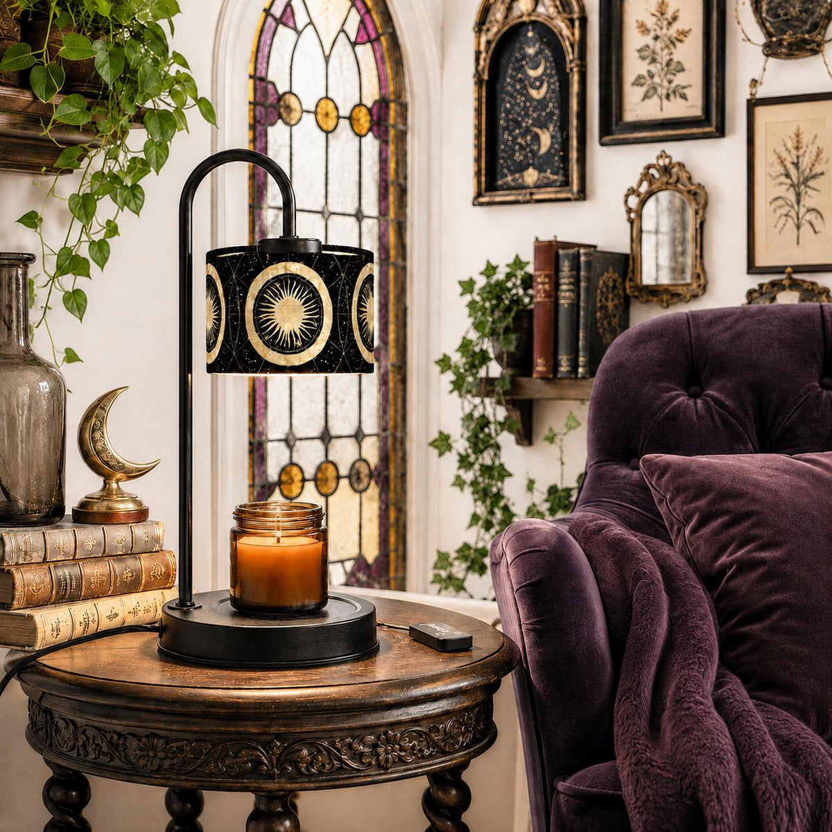 May include: A black metal candle warmer lamp with a curved arm and a cylindrical shade featuring a gold sun and moon celestial pattern. The lamp sits on a round base with a glass jar candle emitting a warm orange glow from the lit wax inside.