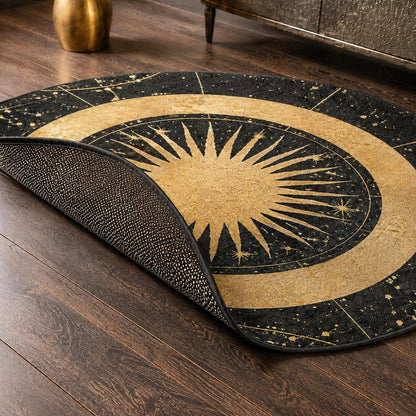May include: A round area rug featuring a black and gold celestial design with a central sunburst motif surrounded by concentric rings and star patterns. The rug has a black underside with a textured, non-slip grip pattern visible where it is folded.