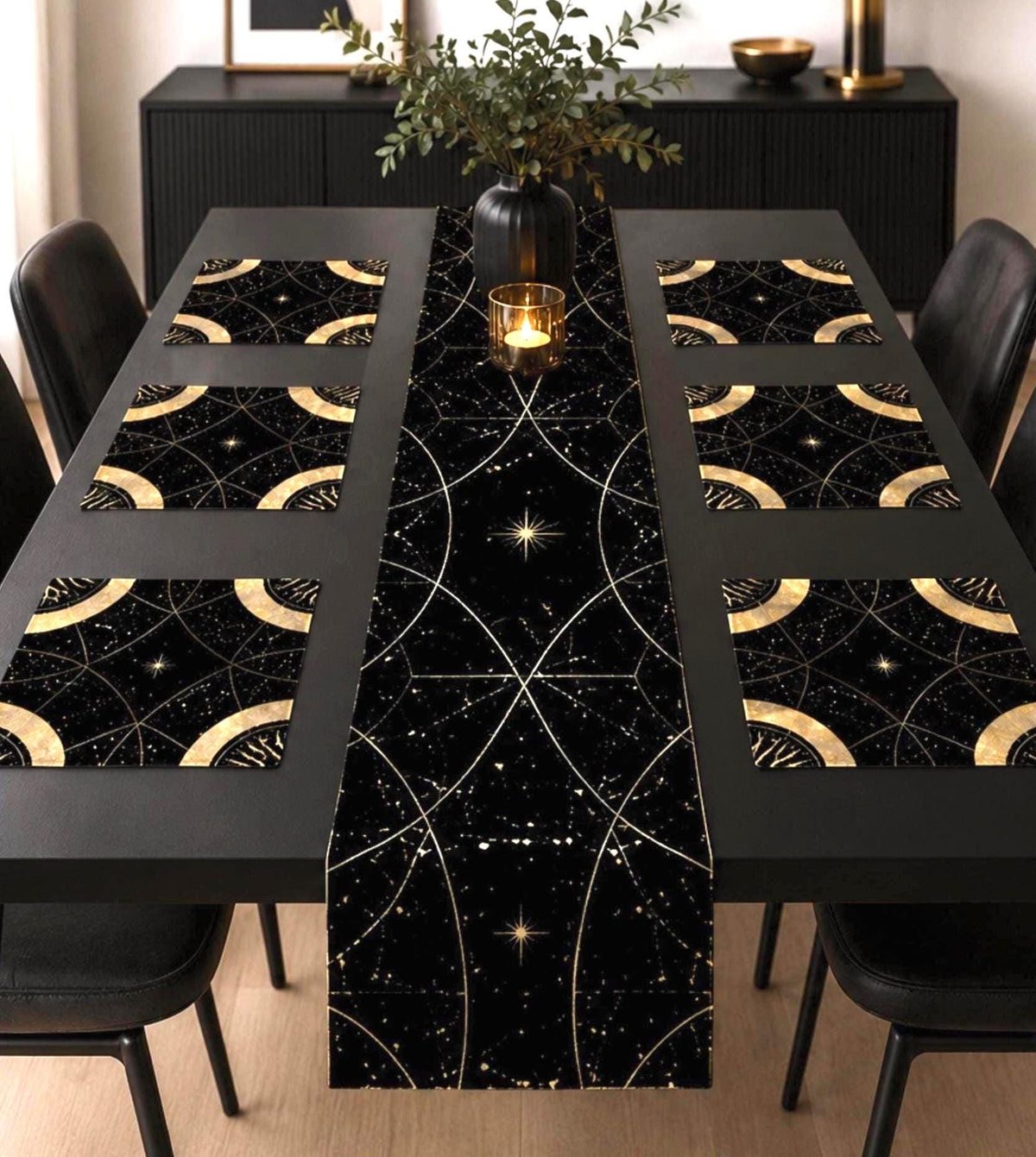 May include: A black table runner and six matching rectangular placemats featuring a gold celestial pattern of intersecting arcs, thin lines, and small starbursts. The fabric has a dark background with a subtle speckled texture throughout.