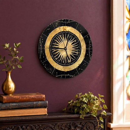 May include: A circular wall clock featuring a black background with gold celestial constellations and a central gold sunburst design. The clock has thin black hands and a gold circular border separating the sunburst from the outer star field.